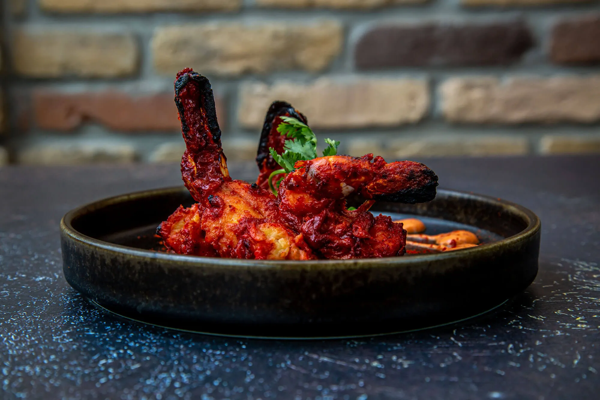 An editorial bone-in tandoori plate against a brick wall